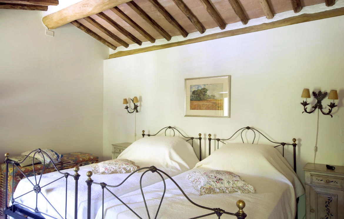 Twin bedroom with iron bed frames, timber ceiling beams and wall lights