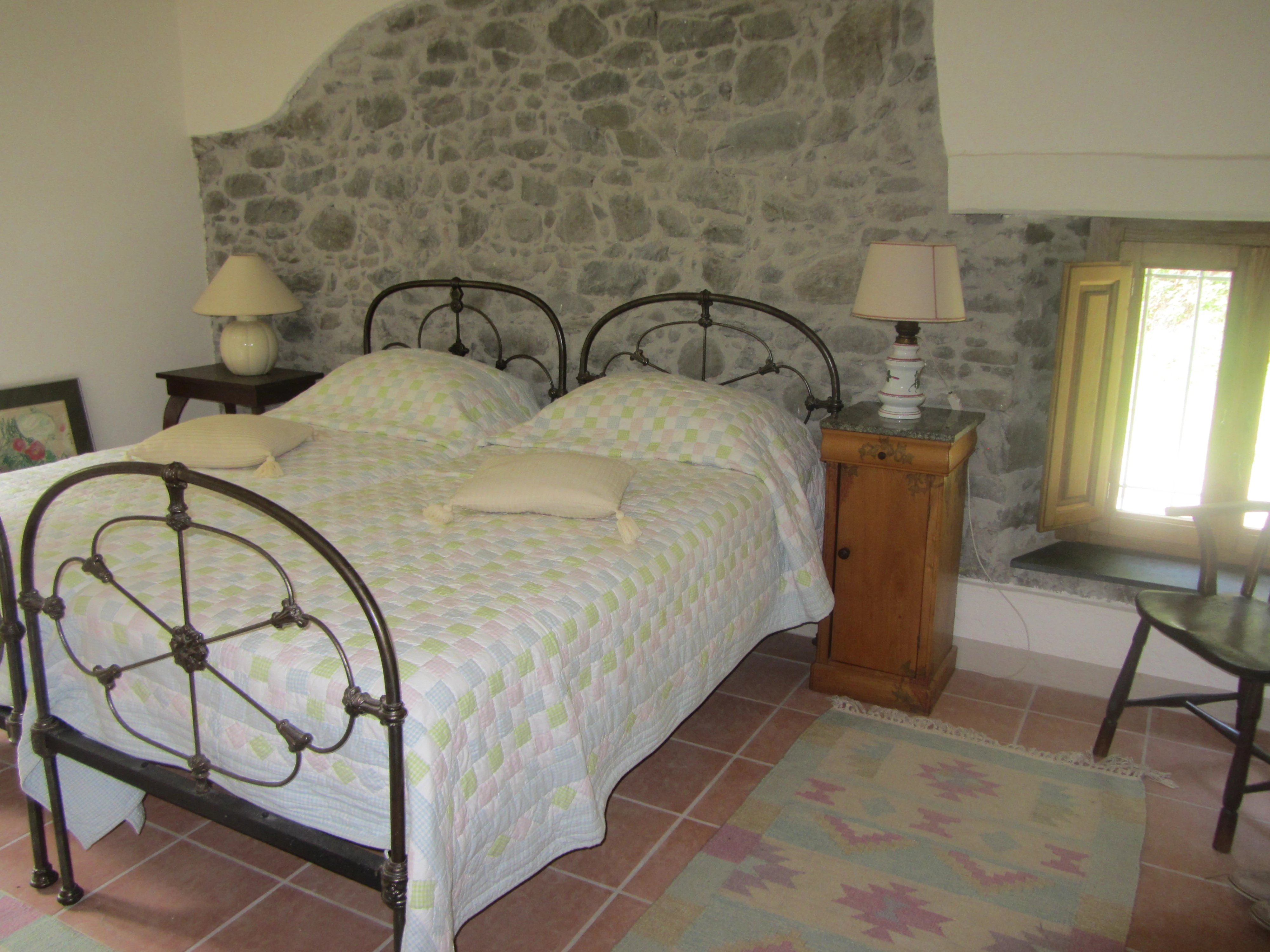 Double bedroom with stone feature wall, iron bed frame and bedside lamps