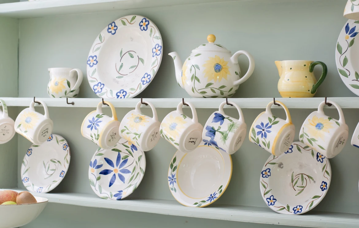 Painted ceramic plates and jugs displayed on open kitchen shelving