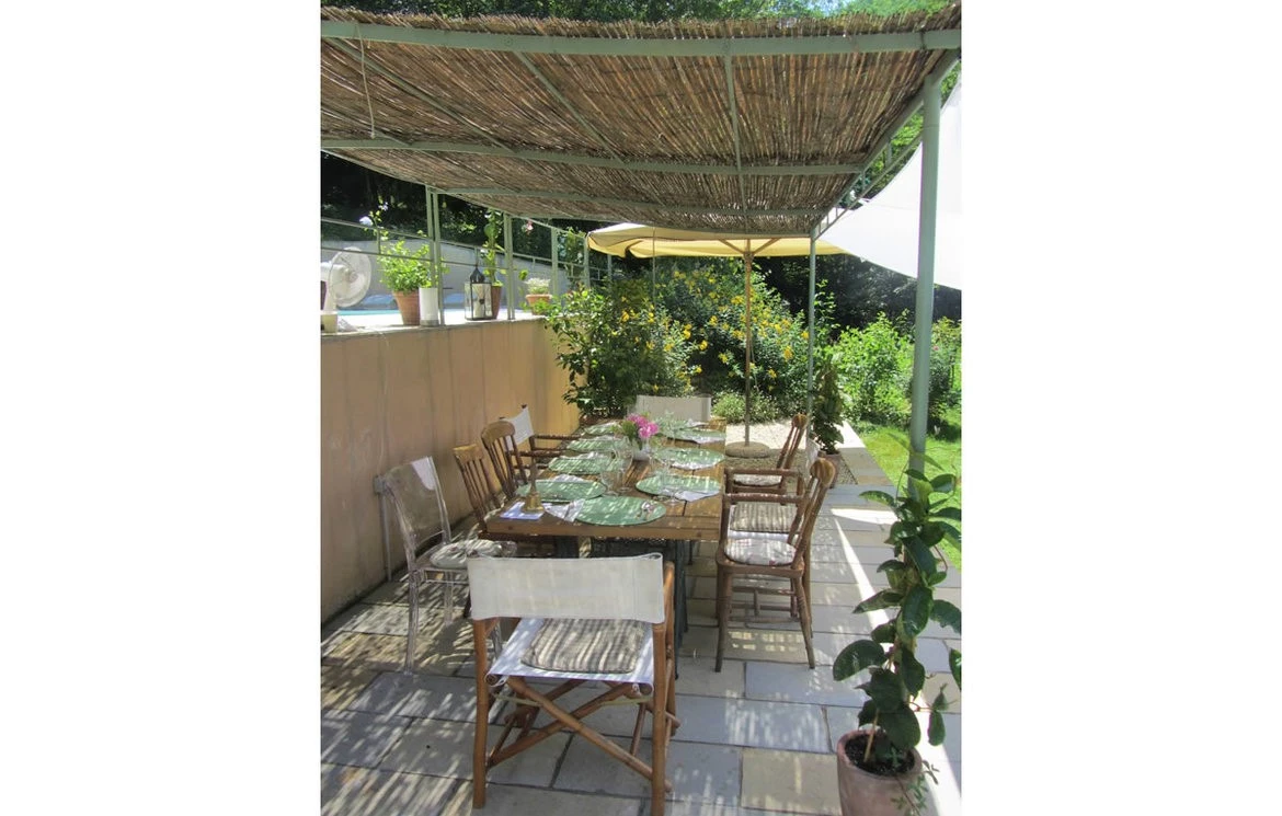 Outdoor dining table set under a shaded terrace canopy