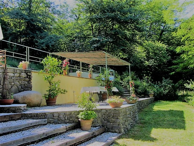 Pergola terrace with potted plants overlooking the lawn and trees