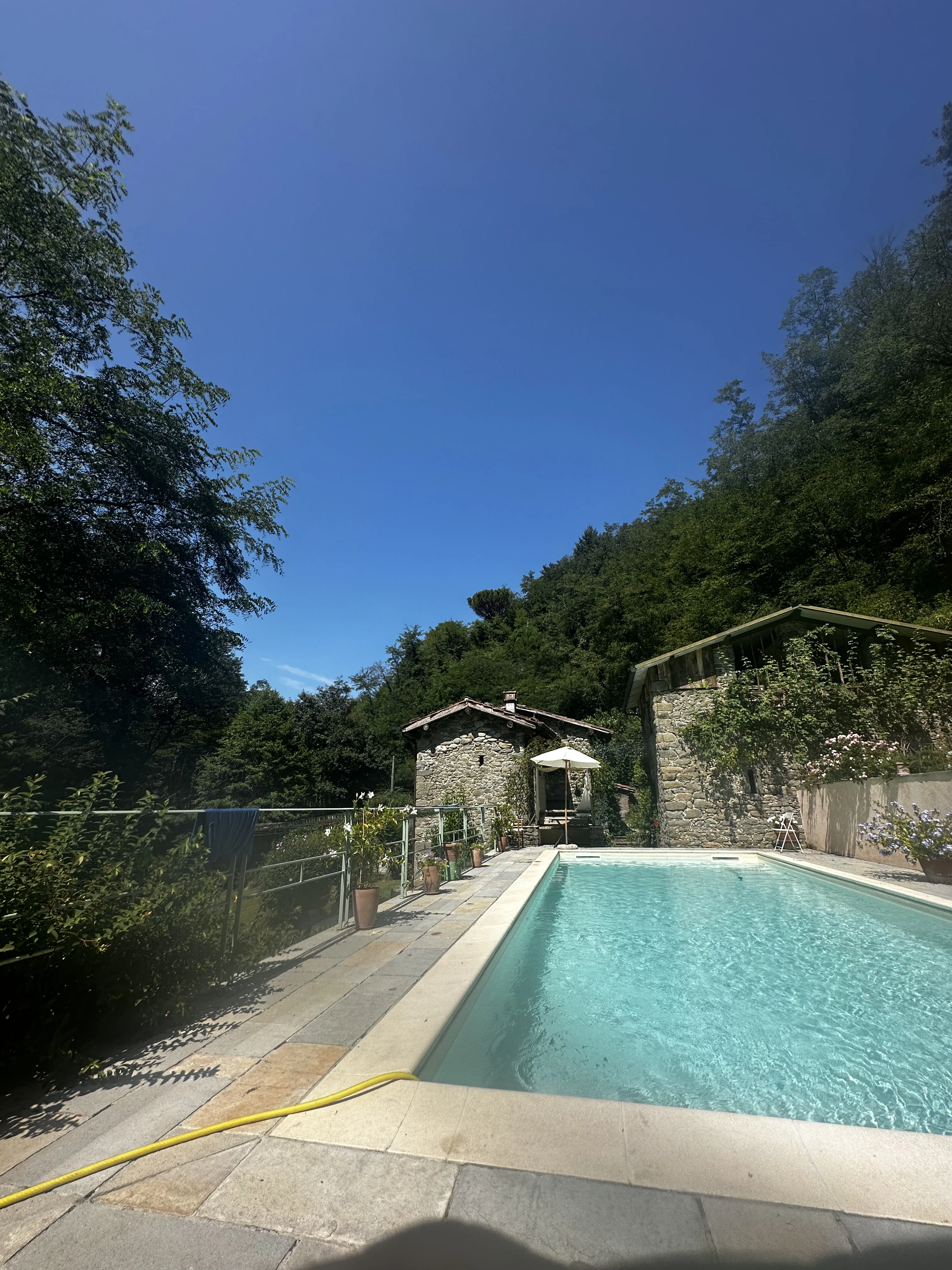 Narrow view along the turquoise swimming pool and stone terrace